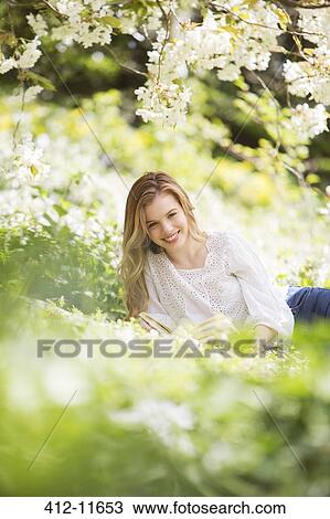 Woman relaxing in grass with book View Large Photo Image Stock Image - Woman relaxing in grass with book. Fotosearch