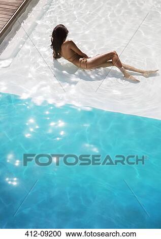 Stock Image - Woman relaxing in swimming pool. Fotosearch