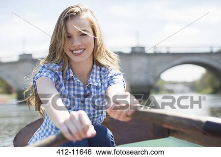 Stock Photograph - Woman rowing boat on river. Fotosearch