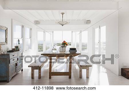 Wooden table and benches in sunny dining room View Large Photo Image Stock Photo - Wooden table and benches in sunny dining room. Fotosearch