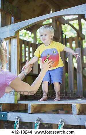 Boy jumping from playset into father's arms View Large Photo Image Picture - Boy jumping from playset into father's arms. Fotosearch
