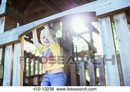 Stock Photograph - Boy playing on play structure outdoors. Fotosearch