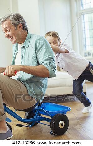 Boy pushing father on tricycle indoors View Large Photo Image Stock Photograph - Boy pushing father on tricycle indoors. Fotosearch