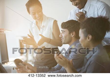 Stock Image - Business people cheering in office. Fotosearch