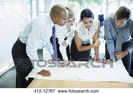Stock Photo - Business people examining blueprints in office. Fotosearch