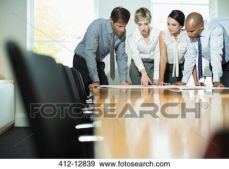 Business people examining blueprints in meeting View Large Photo Image Stock Photo - Business people examining blueprints in meeting. Fotosearch