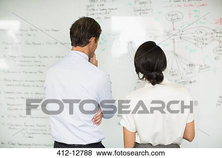 Stock Photo - Business people reading whiteboard in office. Fotosearch