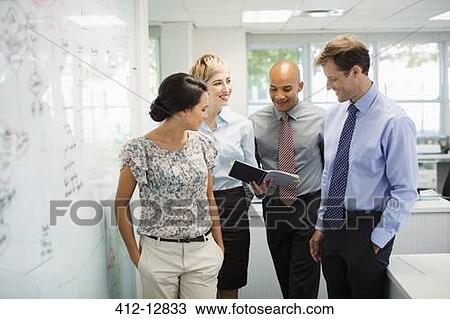 Stock Image - Business people talking at whiteboard in office. Fotosearch