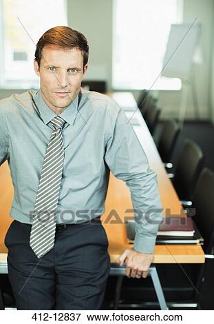 Businessman sitting at edge of conference table View Large Photo Image Stock Photo - Businessman sitting at edge of conference table. Fotosearch