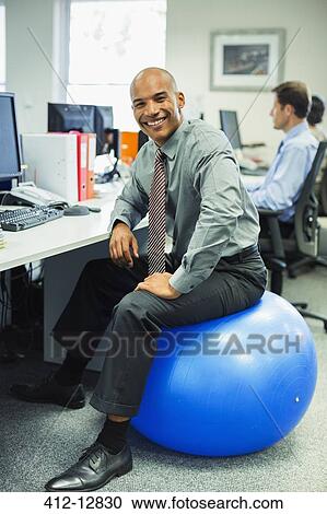 Businessman sitting on fitness ball in office View Large Photo Image Stock Image - Businessman sitting on fitness ball in office. Fotosearch