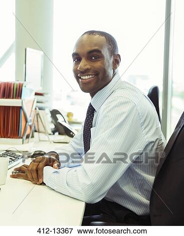 Businessman smiling at desk in office View Large Photo Image Stock Photo - Businessman smiling at desk in office. Fotosearch