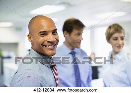 Businessman smiling in office View Large Photo Image Picture - Businessman smiling in office. Fotosearch