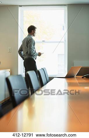 Businessman standing at conference room window View Large Photo Image Stock Image - Businessman standing at conference room window. Fotosearch