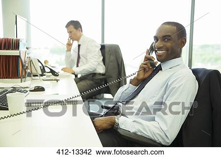 Businessman talking on telephone in office View Large Photo Image Stock Image - Businessman talking on telephone in office. Fotosearch
