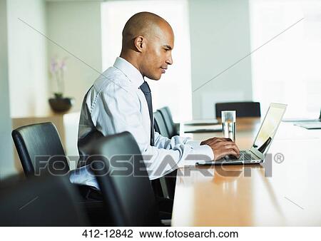 Businessman using laptop at conference table View Large Photo Image Stock Image - Businessman using laptop at conference table. Fotosearch