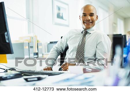 Businessman working at desk in office View Large Photo Image Stock Image - Businessman working at desk in office. Fotosearch