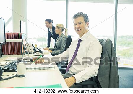 Businessman working at desk in office View Large Photo Image Stock Image - Businessman working at desk in office. Fotosearch