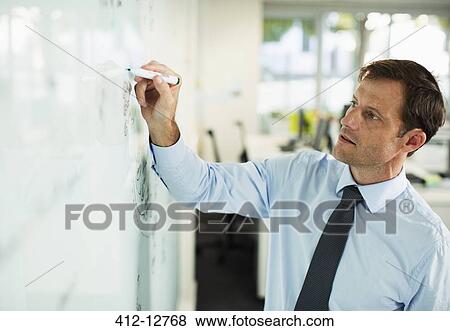 Businessman writing on whiteboard in office View Large Photo Image Stock Photo - Businessman writing on whiteboard in office. Fotosearch