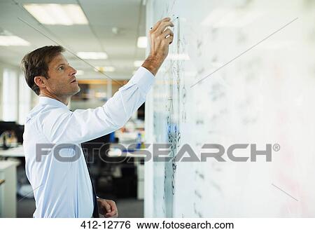 Businessman writing on whiteboard in office View Large Photo Image Stock Photograph - Businessman writing on whiteboard in office. Fotosearch