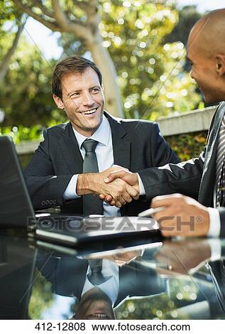 Stock Photo - Businessmen shaking hands outdoors. Fotosearch