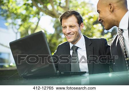 Businessmen using laptop outdoors View Large Photo Image Stock Photography - Businessmen using laptop outdoors. Fotosearch