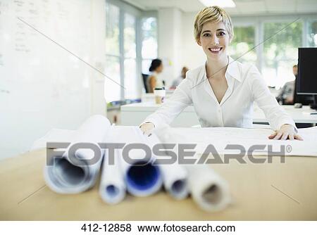Stock Photo - Businesswoman examining blueprints in office. Fotosearch