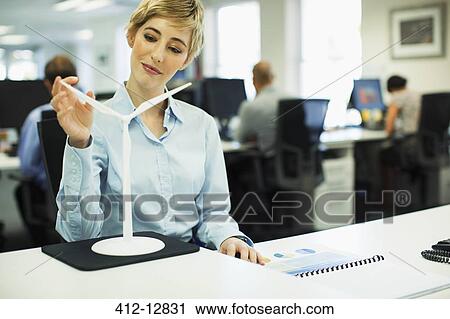 Businesswoman examining toy wind turbine in office View Large Photo Image Stock Image - Businesswoman examining toy wind turbine in office. Fotosearch