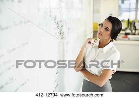 Businesswoman looking at whiteboard in office View Large Photo Image Picture - Businesswoman looking at whiteboard in office. Fotosearch
