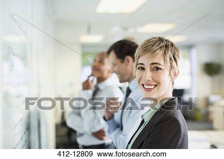 Businesswoman smiling at whiteboard in office View Large Photo Image Stock Photo - Businesswoman smiling at whiteboard in office. Fotosearch