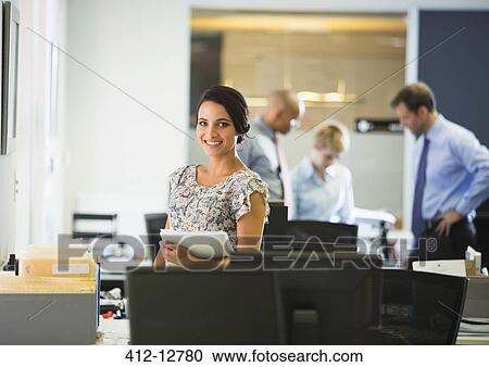 Stock Image - Businesswoman smiling in office. Fotosearch