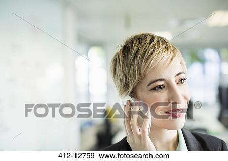 Stock Photo - Businesswoman talking on cell phone in office. Fotosearch