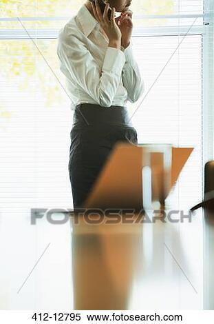 Stock Photography - Businesswoman talking on cell phone in office. Fotosearch