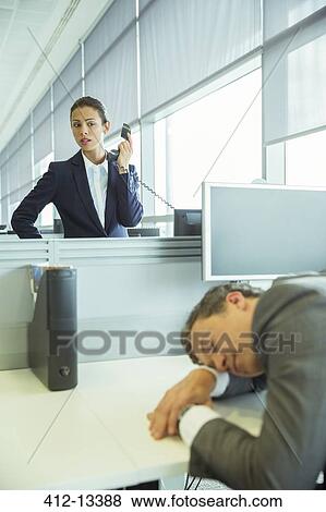 Stock Photo - Businesswoman watching sleeping businessman in office. Fotosearch