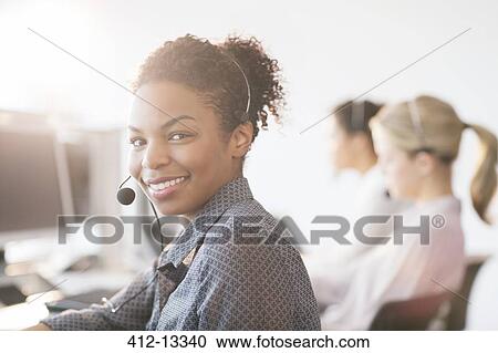 Stock Image - Businesswoman wearing headset in office. Fotosearch