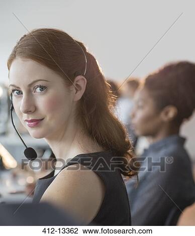 Stock Image - Businesswoman wearing headset in office. Fotosearch