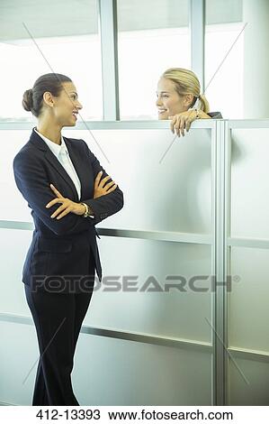 Stock Image - Businesswomen talking in office. Fotosearch
