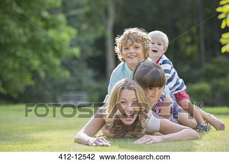 Children laying on mother in grass View Large Photo Image Stock Image - Children laying on mother in grass. Fotosearch