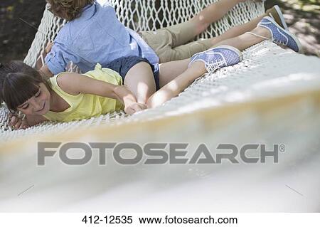 Stock Photography - Children relaxing in hammock outdoors. Fotosearch