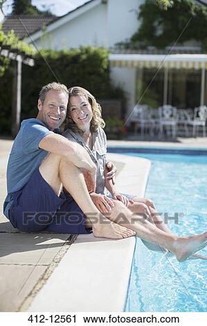 Stock Image - Couple relaxing at poolside. Fotosearch