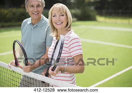 Stock Photo - Couple smiling on tennis court. Fotosearch