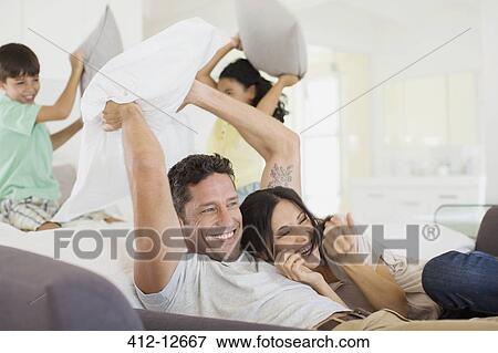 Family enjoying pillow fight in living room View Large Photo Image Stock Photo - Family enjoying pillow fight in living room. Fotosearch