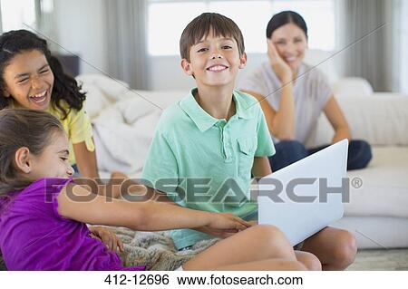 Family using laptop on sofa in living room View Large Photo Image Stock Photograph - Family using laptop on sofa in living room. Fotosearch