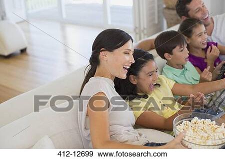 Stock Photo - Family watching movie on sofa in living room. Fotosearch