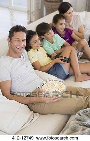 Stock Photo - Family watching TV on sofa in living room. Fotosearch