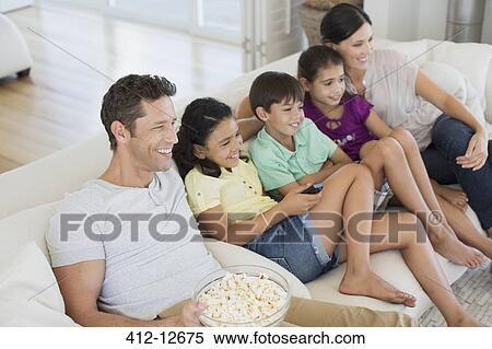 Stock Photography - Family watching TV on sofa in living room. Fotosearch