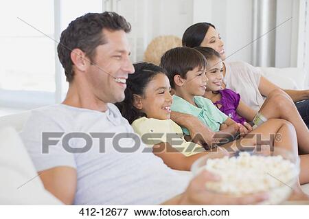 Family watching TV on sofa View Large Photo Image Stock Photo - Family watching TV on sofa. Fotosearch