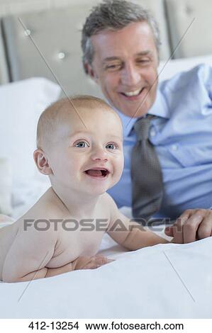 Picture - Father and baby relaxing on bed. Fotosearch