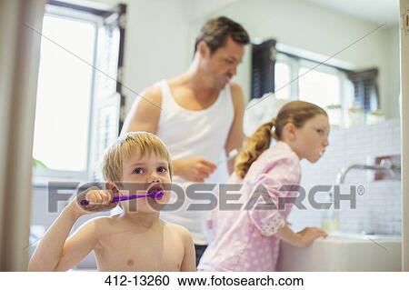 Stock Image - Father and children brushing teeth in bathroom. Fotosearch