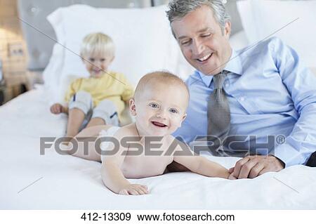 Stock Photo - Father and children playing on bed. Fotosearch