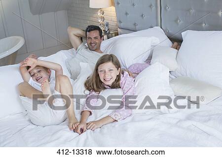 Father and children relaxing on bed View Large Photo Image Stock Photo - Father and children relaxing on bed. Fotosearch